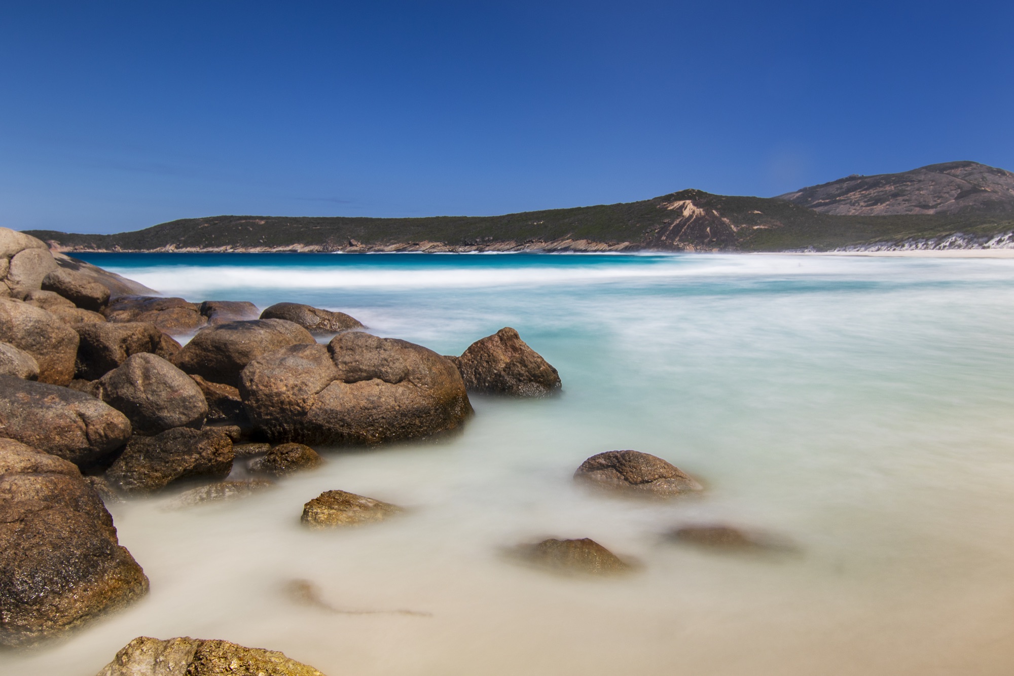 Turquoise water against rocks on a sunny day.